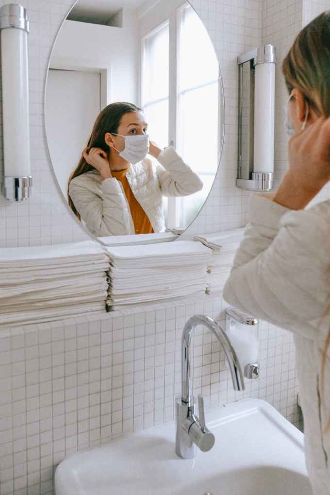 woman with a face mask fixing her hair